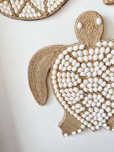 two pieces of art made out of jute string and beaded with white beads