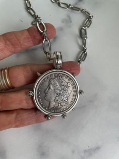 a person is holding a coin on a silver chain that has been attached to it