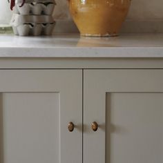 two yellow vases sitting on top of a white countertop next to each other