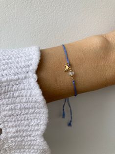 a woman's arm wearing a blue bracelet with a gold star charm on it