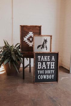 three wooden signs sitting on top of a floor next to a potted plant in a room