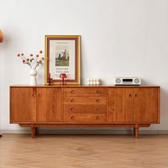 a wooden dresser sitting next to a lamp on top of a hard wood floored floor