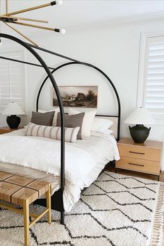 a bedroom with white bedding and black iron frame canopy over the bed, along with two nightstands