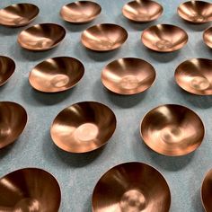 many shiny metal bowls are lined up on a table together, with one in the middle surrounded by smaller ones