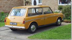 an old yellow car parked in front of a house