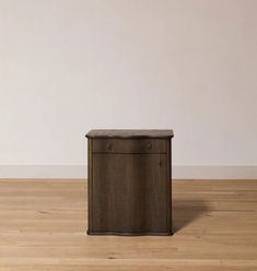 a small wooden cabinet sitting on top of a hard wood floor next to a white wall