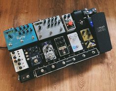 an assortment of pedals and amps sitting on top of a wooden floor