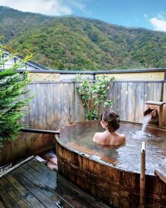 a woman is sitting in an outdoor hot tub