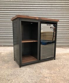 an empty storage cabinet sitting in front of a garage door with its doors open and shelves on the outside