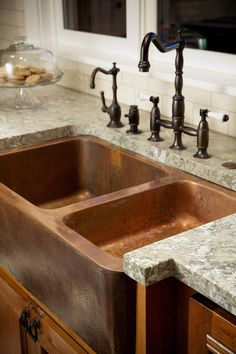 a kitchen sink sitting under a faucet next to a window