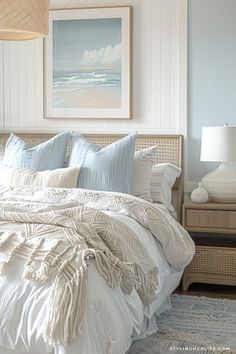 a bed with white linens and pillows in a bedroom next to a painting on the wall