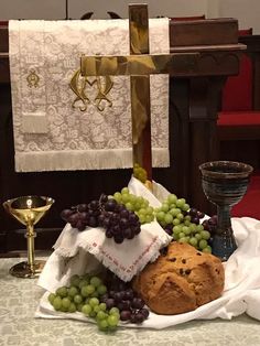 grapes, bread and chalice on a table in front of a cross