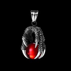 a red apple is in the middle of a snake's claw pendant on a black background