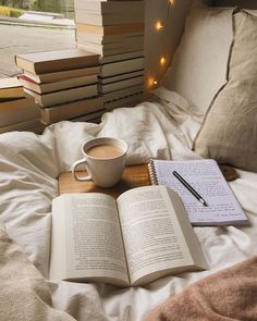 an open book and cup of coffee on a bed