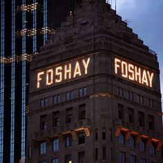 a tall building with lights on it's side and the words foshay lit up at night