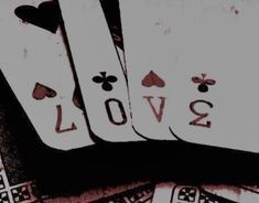 four playing cards with the word love written on them in black and white ink, surrounded by other playing cards