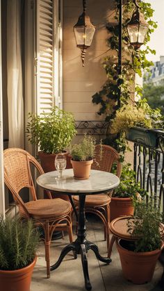 an outdoor table and chairs with potted plants on the front porch, along with hanging lights