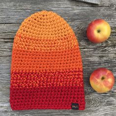 an orange and red knitted hat next to two apples