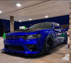 a blue dodge charger parked in front of a gas station with its lights on