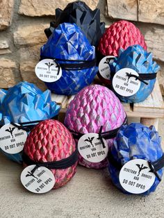 several different colored balls with labels on them sitting in front of a stone wall,