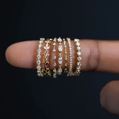 a woman's hand with five gold rings on it and four diamond bracelets