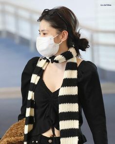 a woman wearing a black and white striped scarf with a face mask over her mouth