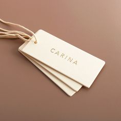 three tags with the word carina on them hanging from strings against a brown background