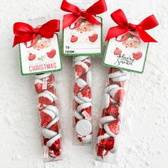 three candy sticks wrapped in red and white paper with bows on them, sitting next to each other