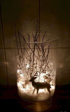 a glass vase filled with twigs and a deer figurine