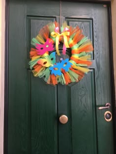 a green door with a wreath made out of tissue paper and colorful streamers on it