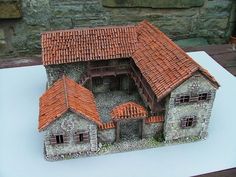 a model of a house made out of clay and stone bricks with an orange roof