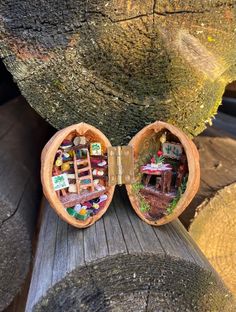 an open wooden box with miniature houses in it sitting on top of a piece of wood