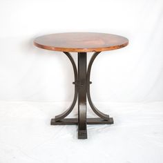 a round wooden table sitting on top of a metal stand