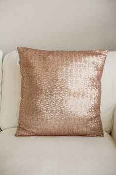 a white couch with a pink pillow on it's back and gold sequins