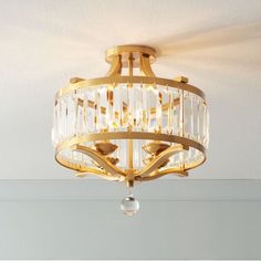 a golden chandelier hanging from the ceiling in a room with white walls and flooring