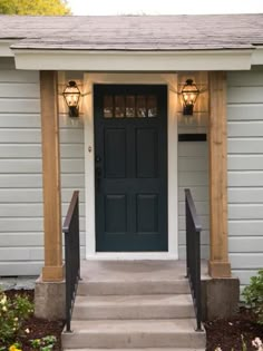 the front door of a house with two lights on it and steps leading up to it