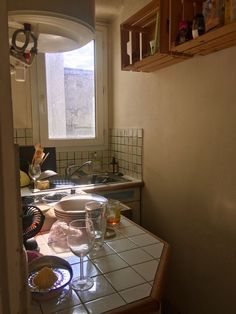 the kitchen counter is covered with dishes and glasses on it, as well as an open window