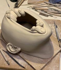 a clay sculpture is being made on a table with other tools and supplies around it