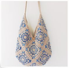 a crocheted bag hanging on a wall with blue and white flowers in it