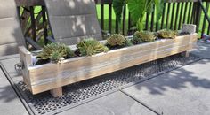 a wooden planter filled with succulents on top of a metal grate