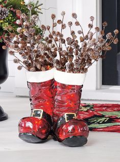 two red boots sitting next to each other in front of a black potted plant