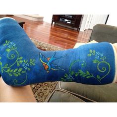 a woman's legs with blue socks and flowers on them, in front of a couch