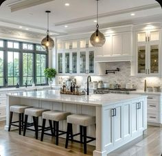 a large kitchen with white cabinets and marble counter tops, stools at the island