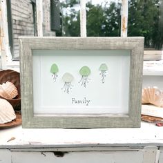 an old frame with three jellyfish on it sitting next to shells and seashells