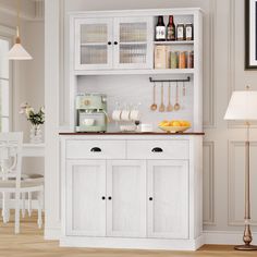 a kitchen with white cupboards and wooden flooring next to a dining room table