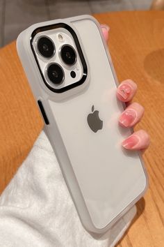 a woman's hand holding an iphone case on top of a wooden table