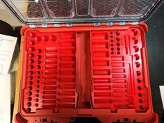 an open red plastic case filled with lots of screwdrives and other tools sitting on top of a table