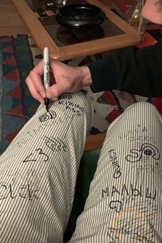 a person sitting on the floor holding a cell phone and writing on their leggings