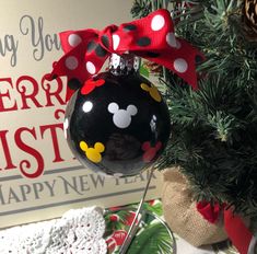 a christmas ornament hanging from the side of a tree with a red bow