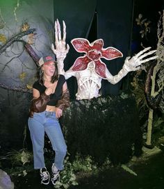 a woman standing in front of a fake flower with her hands out to the side